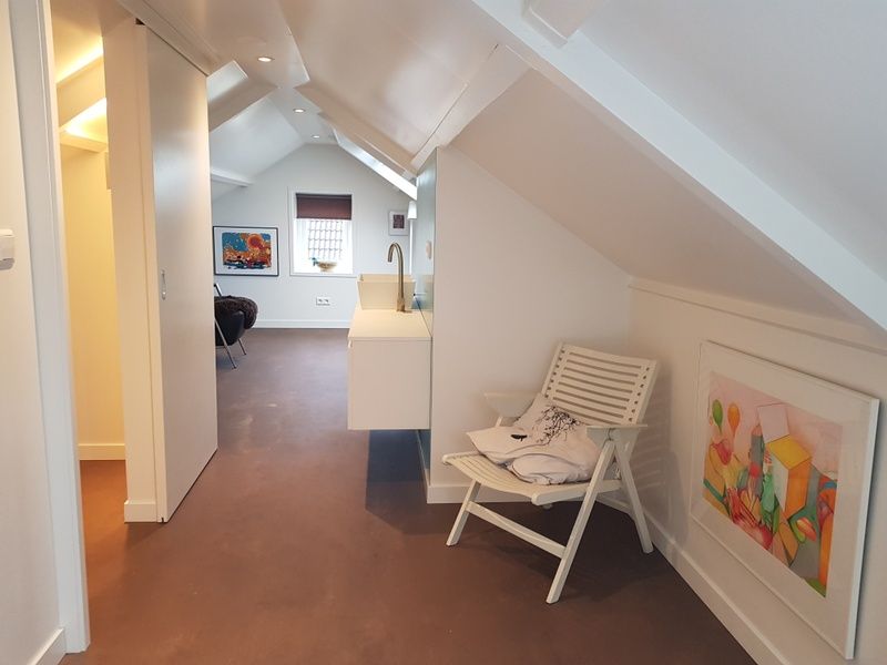 Stijlvolle zolderruimte in Bungalow Schelpenoord - Vakantiehuis De Oester, De Cocksdorp, Texel, met zitgedeelte en kunst aan de muur.