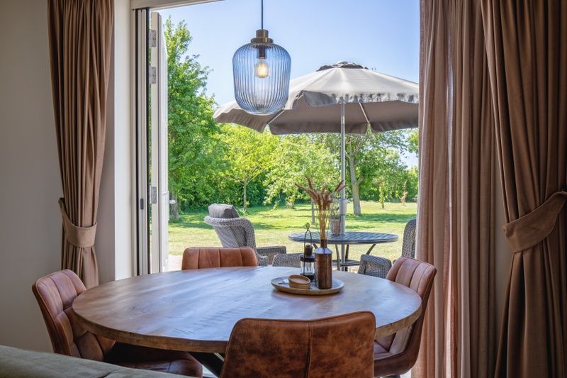 Eethoek met uitzicht op de tuin bij Appartement B in De Cocksdorp, Texel, ideaal voor buiten dineren.