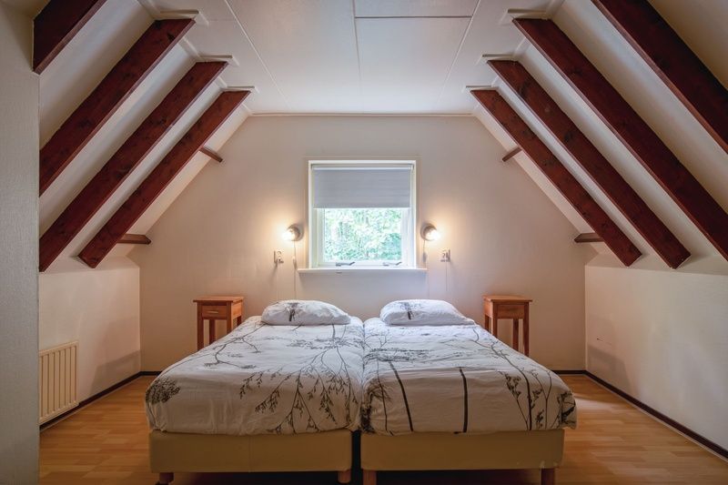 Sfeervolle slaapkamer in Huisje Krimweg, vakantiehuis in De Cocksdorp Texel met houten balken en natuurlijk licht.