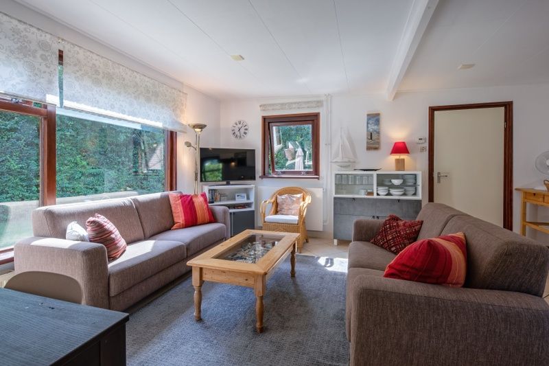 Gemuetliches Wohnzimmer des Ferienhauses Slufterduin 092 in De Cocksdorp, Texel mit bequemen Sofas und viel Tageslicht.