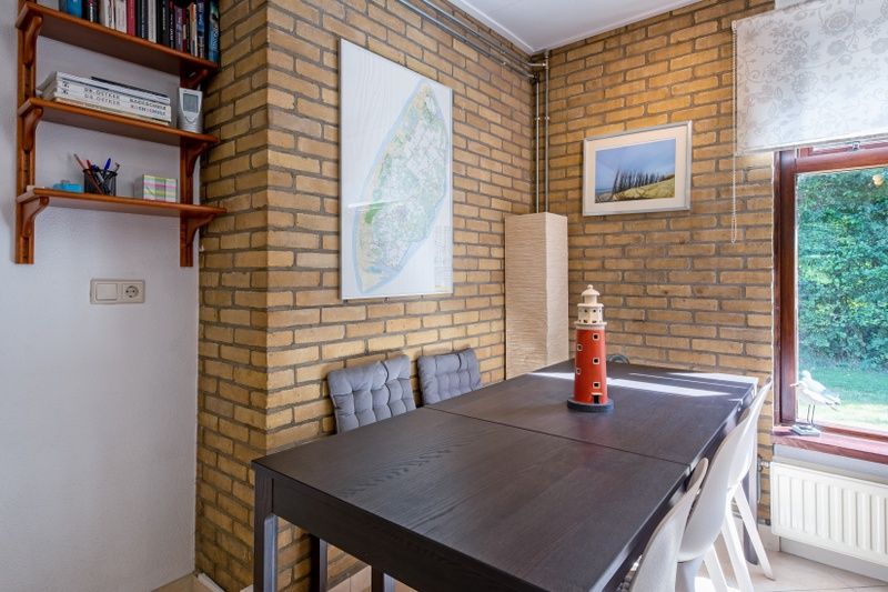 Essecke im Ferienhaus Slufterduin 092, De Cocksdorp, Texel mit moderner Einrichtung und Blick auf die gruene Umgebung.