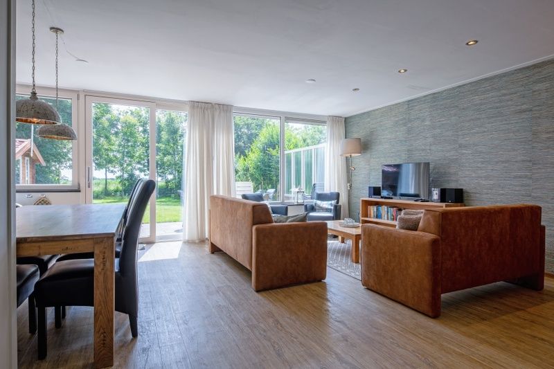 Bright dining room and living room in Holiday home Slufterhoek 132, De Cocksdorp, Texel overlooking the green surroundings.