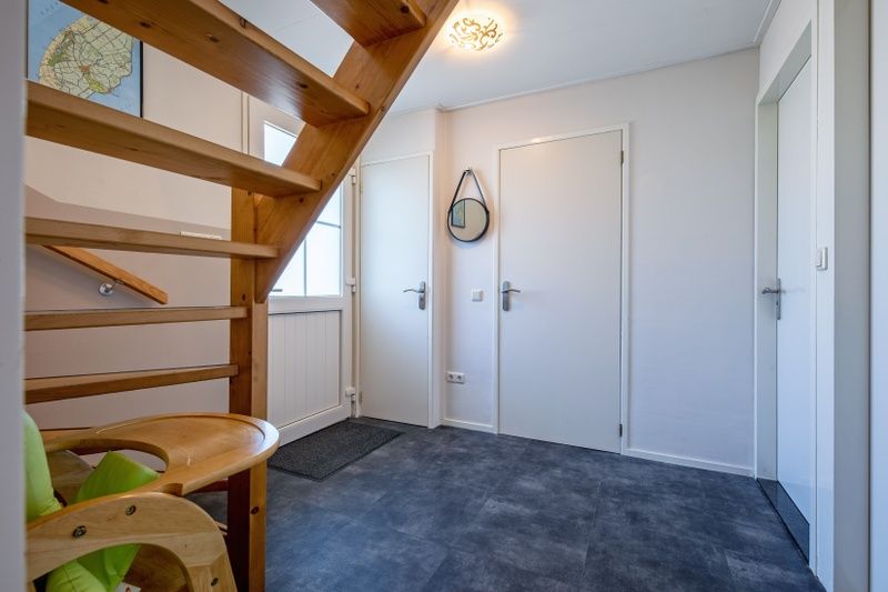 Entrance to Holiday home Slufterhoek 132 in De Cocksdorp, Texel with wooden stairs and practical layout.