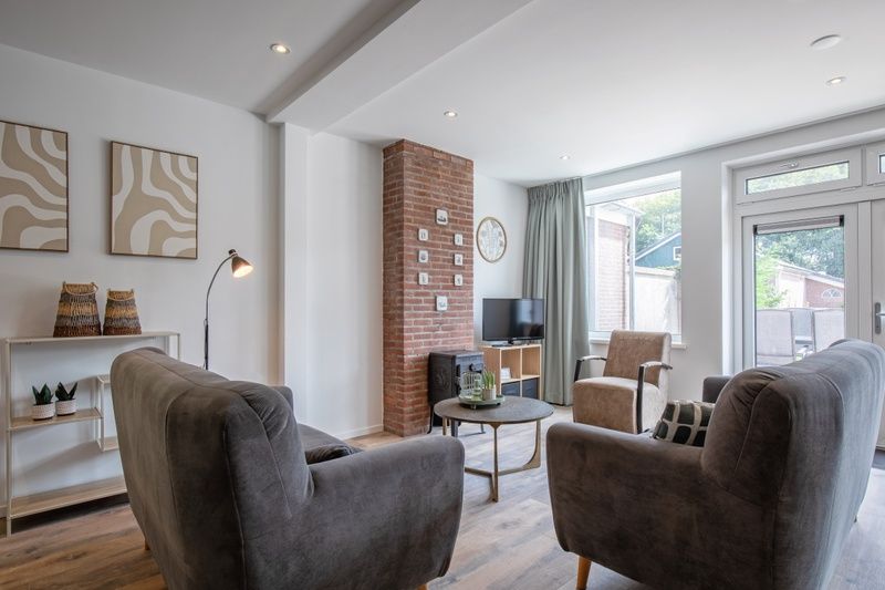 Lichte woonkamer van Vakantiehuis Slufterhoek 104 in De Cocksdorp, Texel met moderne meubels en grote ramen.