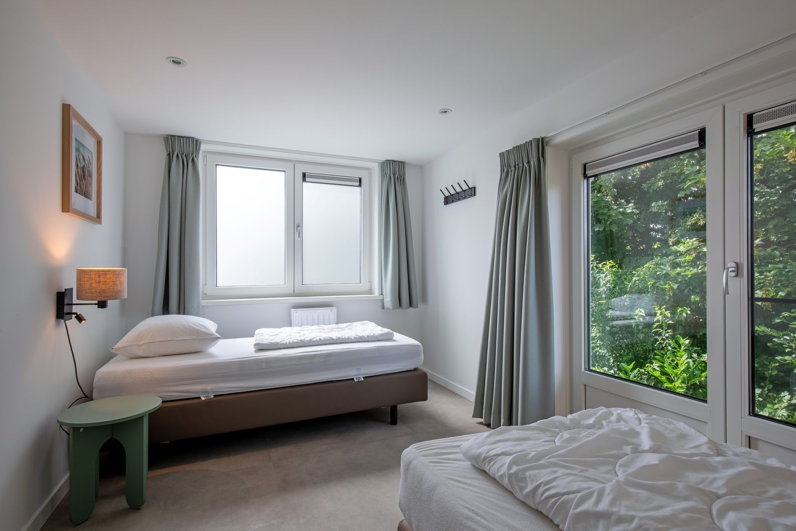 Lichte slaapkamer in Vakantiehuis Slufterhoek 104, De Cocksdorp, Texel met eenpersoonsbedden en uitzicht op de tuin.