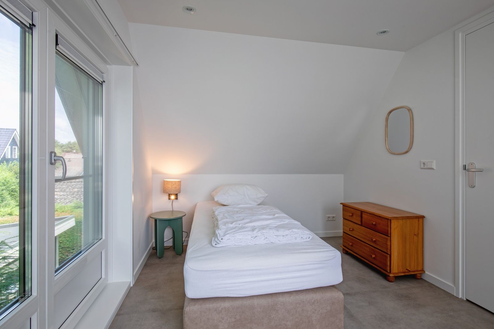 Knusse slaapkamer in Vakantiehuis Slufterhoek 104, De Cocksdorp, Texel met eenpersoonsbed en houten ladekast.