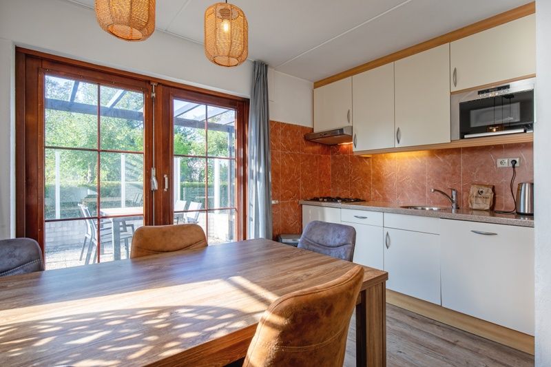Gezellige keuken en eetruimte in Villapark Residentie Texel nr. 711, vakantiehuis in De Cocksdorp, Texel, met uitzicht op terras en tuin.