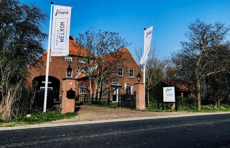 Vakantiehuisje in De Cocksdorp, Texel met charmante gevel en rode dakpannen, perfect voor een ontspannen verblijf op de Waddeneilanden.