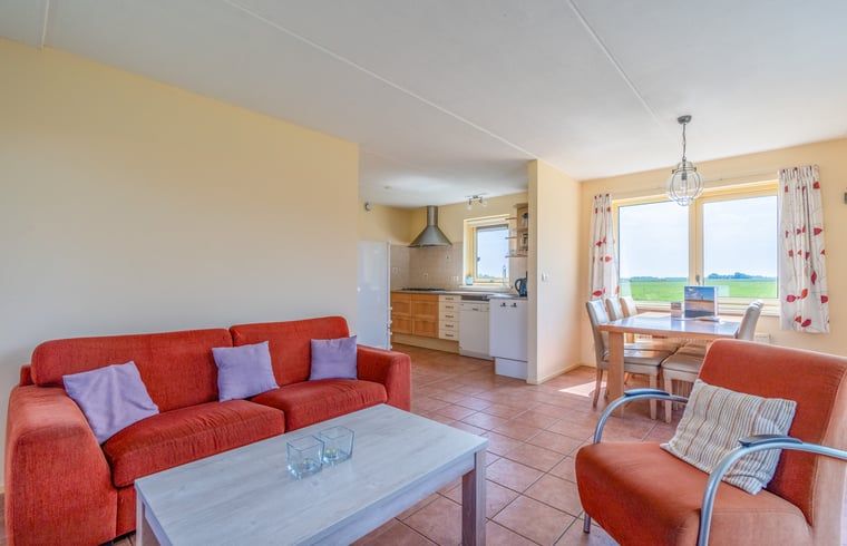 Gezellige woonkamer van Vakantiehuisje in De Cocksdorp, Texel, met open keuken en uitzicht op de groene omgeving van de Waddeneilanden.