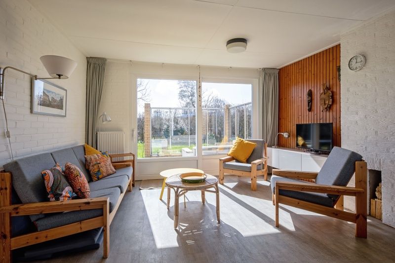 Lichte woonkamer van Vakantiehuis Slufteroord 292 in Bungalowpark Slufteroord, De Cocksdorp, Texel, met uitzicht op de tuin.