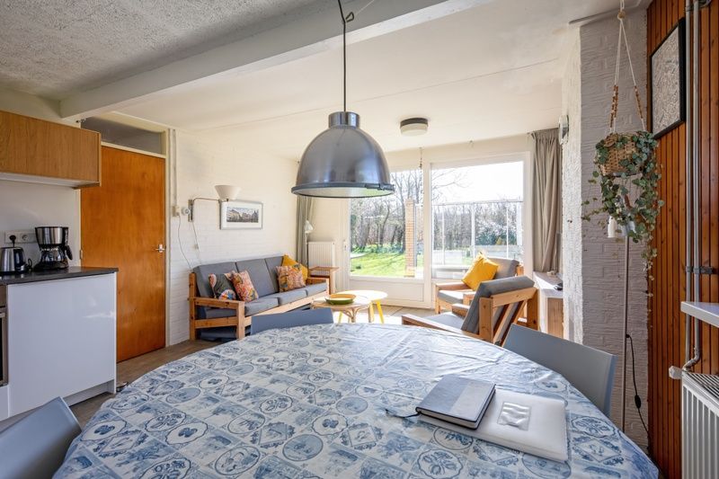 Eetruimte en woonkamer in Vakantiehuis Slufteroord 292, Bungalowpark Slufteroord, De Cocksdorp, Texel, met uitzicht op de tuin.