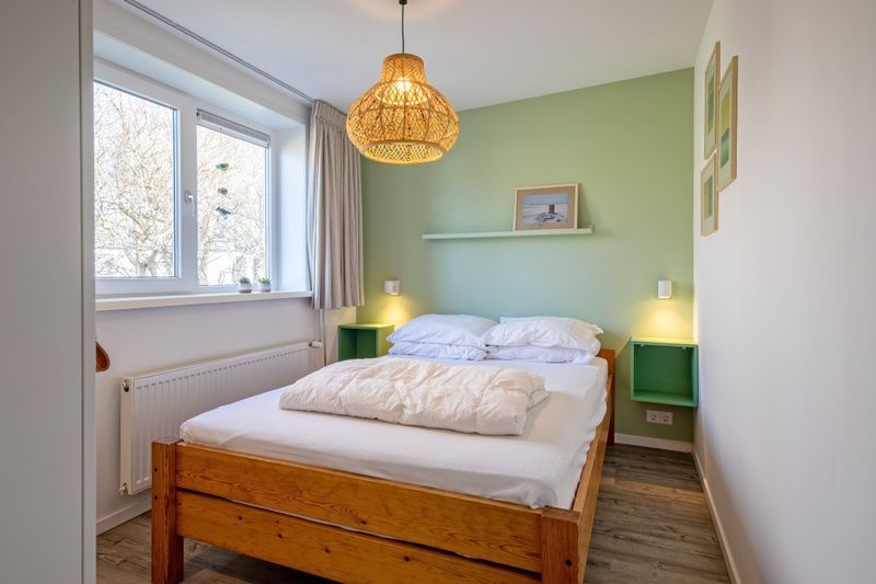 Sfeervolle slaapkamer in Vakantiehuis Slufteroord 292, Bungalowpark Slufteroord, De Cocksdorp, Texel, met veel natuurlijk licht.