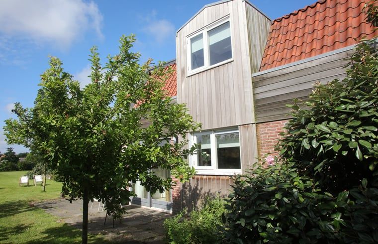 Exterieur van Vakantiehuis in De Cocksdorp, Texel, omgeven door groene natuur en een zonnige tuin, Waddeneilanden.