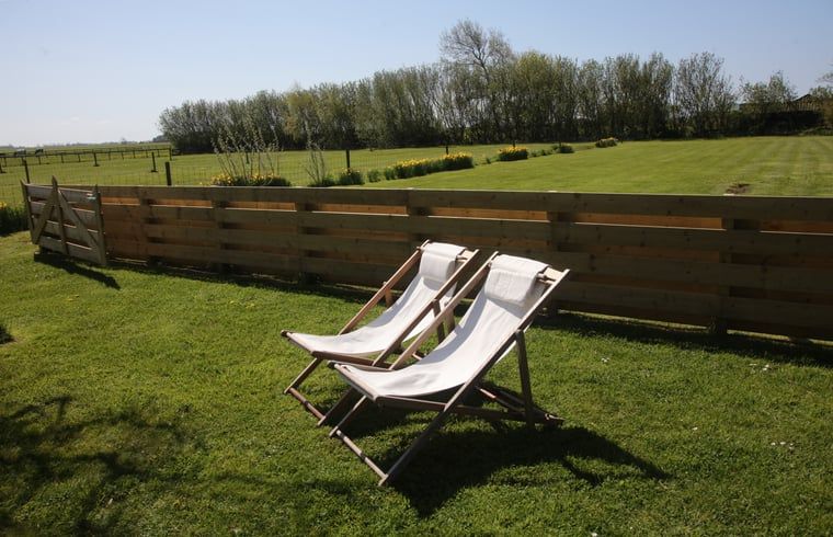 Relax in de ligstoelen van Vakantiehuis in De Cocksdorp, Texel, met uitzicht op groene velden en natuur op de Waddeneilanden.
