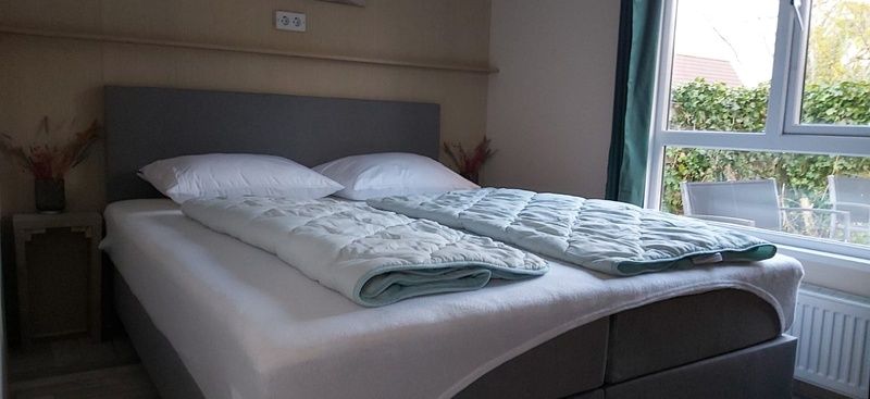 Cozy bedroom in Chalet Duunzicht, a vacation home in De Cocksdorp, Texel, with comfortable bed and view of the green surroundings.