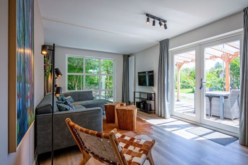 Bright living room of Holiday home D 690 in De Cocksdorp, Texel, with modern furnishings and views of the terrace and nature.
