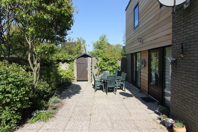 Enjoy the sunny garden of Holiday home A 167 in De Cocksdorp, Texel, with a spacious terrace surrounded by greenery on the Wadden Islands.