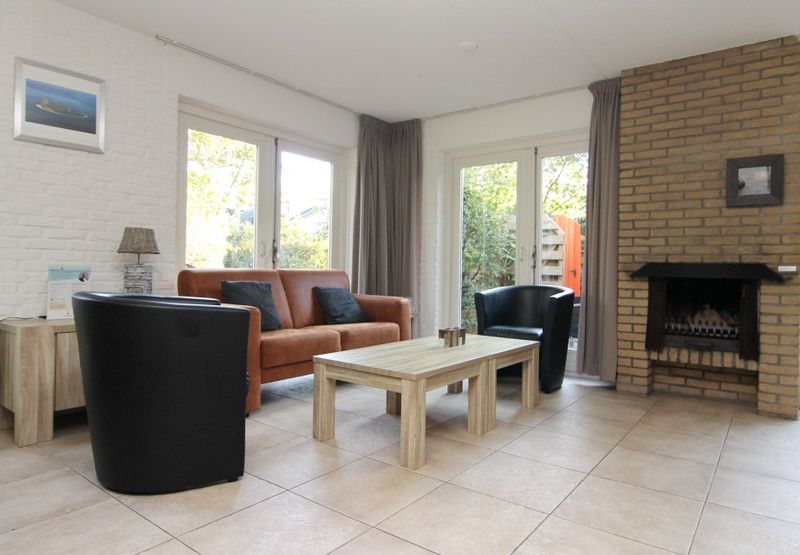 Gezellige woonkamer van Vakantiehuis B 053 in De Cocksdorp, Texel, met comfortabele zitruimte en openslaande deuren naar de tuin.