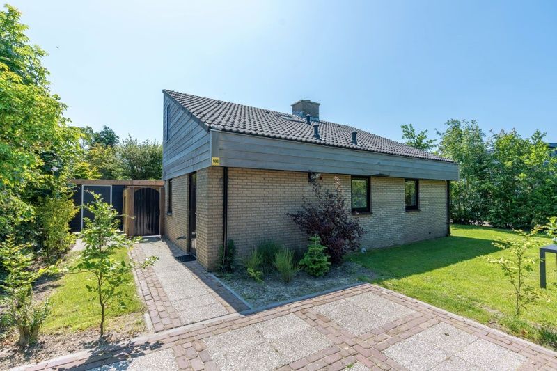 Vakantiehuis A 103 in De Cocksdorp, Texel, biedt een serene buitenruimte met groene omgeving en zonnig terras, ideaal voor ontspanning.