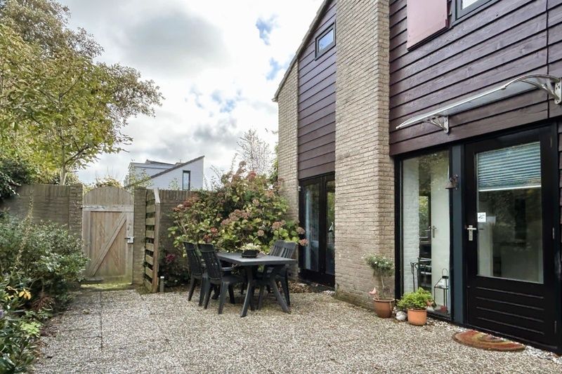 Entspannen Sie sich auf der sonnigen Terrasse des Ferienhauses B 203 in De Cocksdorp, Texel, umgeben von gruener Natur und rustikalem Charme.