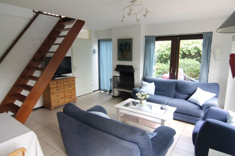 Gemuetliches Wohnzimmer des Ferienhauses B 203 in De Cocksdorp, Texel. Gemuetliche Sitzecke mit Blick auf die gruene Umgebung der Watteninseln.