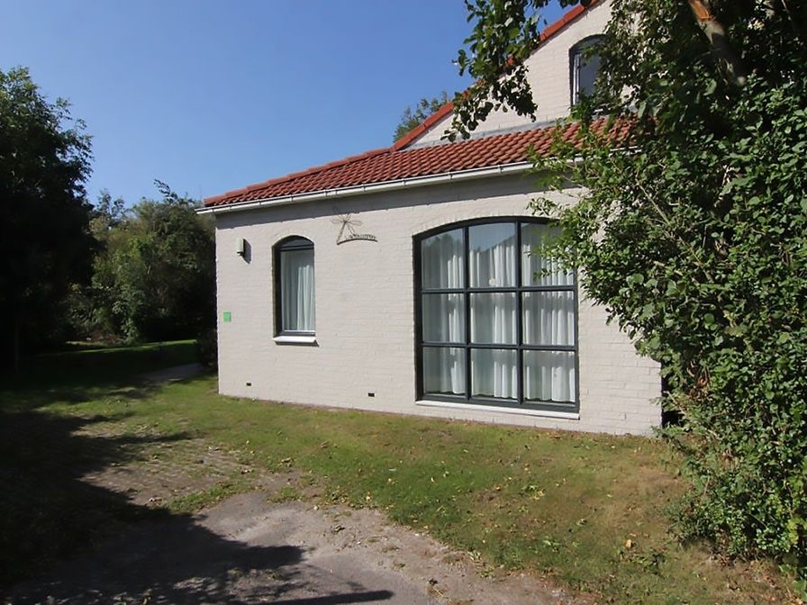 Vakantiehuis D 603 in De Cocksdorp, Texel, biedt een serene buitenruimte met groene tuin en charmante gevel, perfect voor ontspanning.
