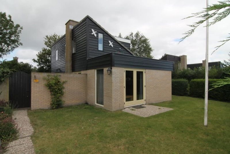 Vakantiehuis A 245 in De Cocksdorp, Texel, biedt een charmante buitenkant met een groene tuin, ideaal voor een ontspannen verblijf op de Waddeneilanden.