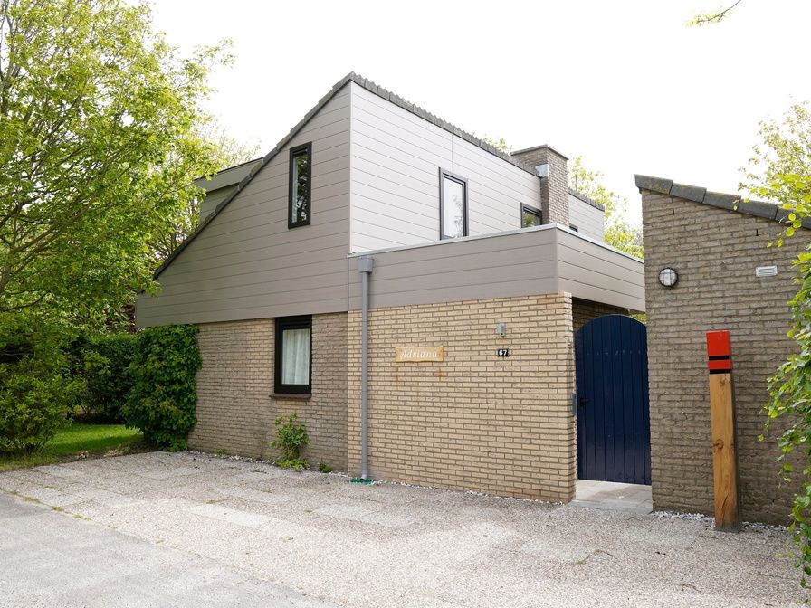 Vakantiehuis C 067 in De Cocksdorp, Texel biedt een charmante buitenkant omgeven door groen, ideaal voor een ontspannen verblijf op de Waddeneilanden.