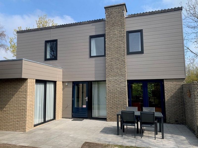 Vakantiehuis C 067 in De Cocksdorp, Texel, toont een modern terras met buitenmeubilair, ideaal voor ontspanning op de Waddeneilanden.