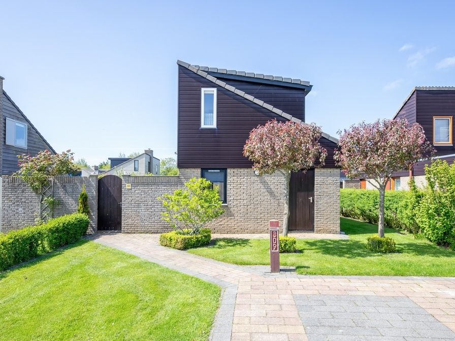 Vacation home A 309 in De Cocksdorp, Texel, offers a charming exterior with green garden and modern architecture on the Wadden Islands.