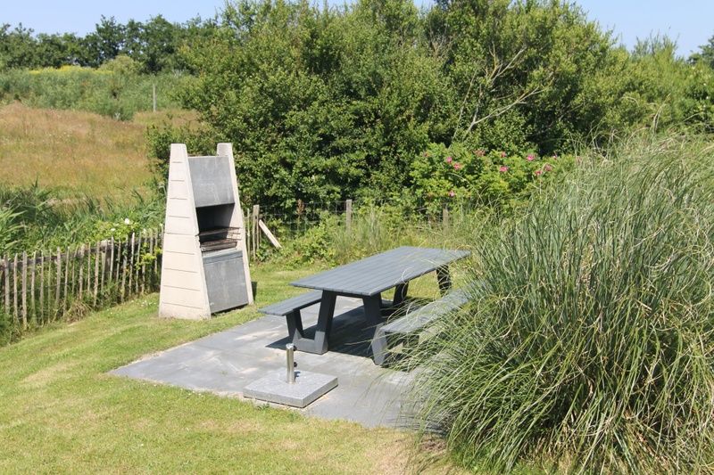 Geniet van de buitenruimte bij Vakantiehuis D 477 in De Cocksdorp, Texel met een gezellige barbecue en picknicktafel te midden van de natuur.