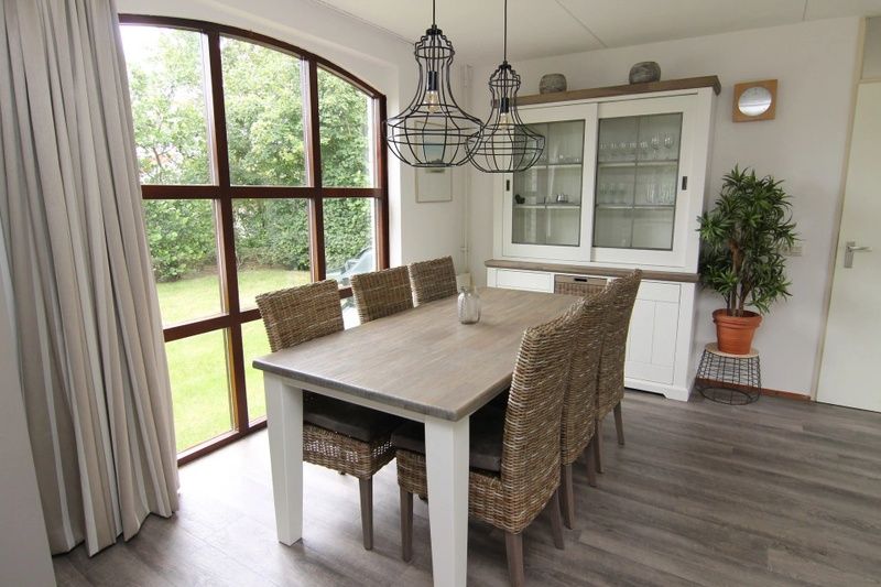 Gezellige eetkamer in Vakantiehuis E 632, De Cocksdorp, Texel met uitzicht op de groene tuin en moderne inrichting.
