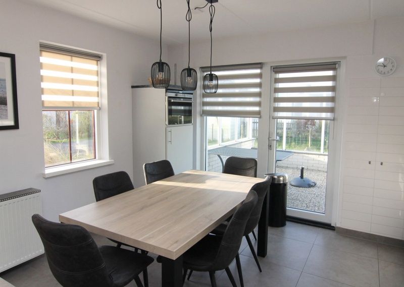 Moderne eetkamer in Vakantiehuis D 481, De Cocksdorp, Texel met ruime tafel en uitzicht op terras.
