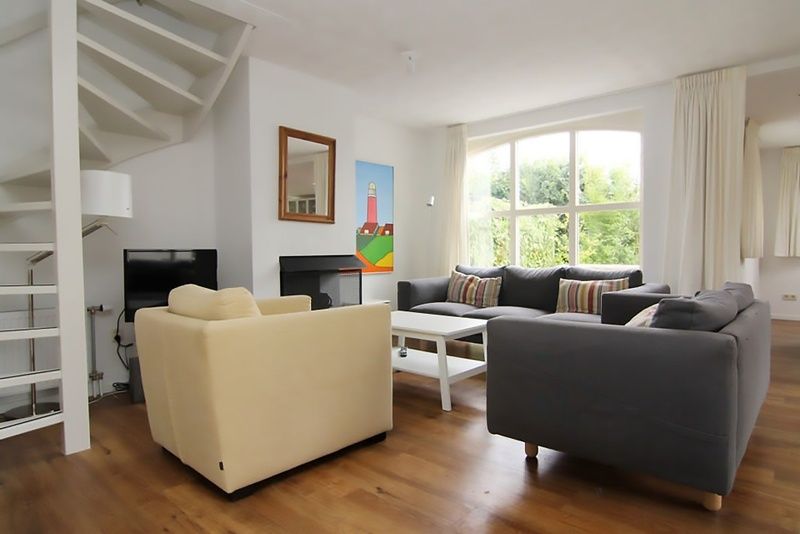 Gezellige woonkamer in Vakantiehuis D 622, De Cocksdorp, Texel. Comfortabele zithoek met uitzicht op de tuin, perfect voor ontspanning.