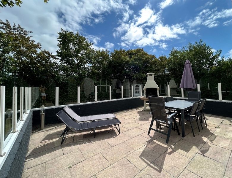 Geniet van het ruime terras van Vakantiehuis E 417 in De Cocksdorp, Texel, met comfortabele ligstoelen en een sfeervolle buitenhaard.