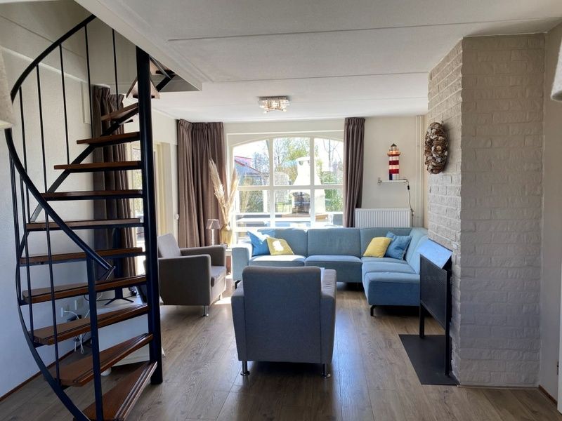 Gezellige woonkamer in Vakantiehuis E 417, De Cocksdorp, Texel met moderne inrichting en uitzicht op de groene omgeving.