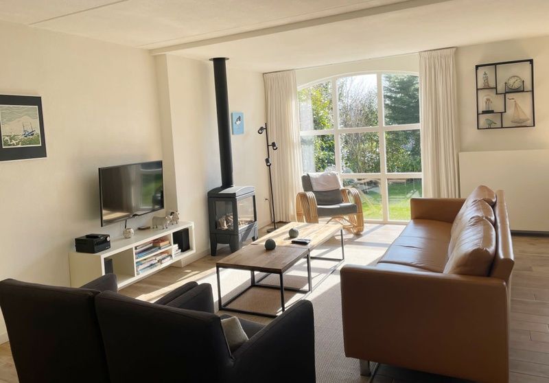 Gemuetliches Wohnzimmer im Ferienhaus D 748, De Cocksdorp, Texel mit moderner Einrichtung und grossen Fenstern fuer eine schoene Aussicht auf den Garten.