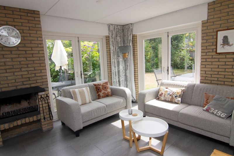 Gezellige woonkamer van Vakantiehuis B 281 in De Cocksdorp, Texel, met comfortabele banken en uitzicht op de groene tuin.