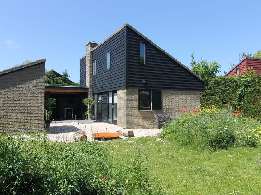 Vakantiehuis C 081 in De Cocksdorp, Texel, biedt een charmant terras met uitzicht op een weelderige tuin en moderne architectuur.