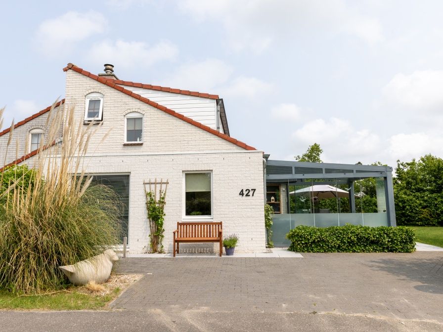 Vakantiehuis D 427 in De Cocksdorp, Texel, biedt een charmante buitenkant en een uitnodigende veranda voor een ontspannen verblijf op de Waddeneilanden.