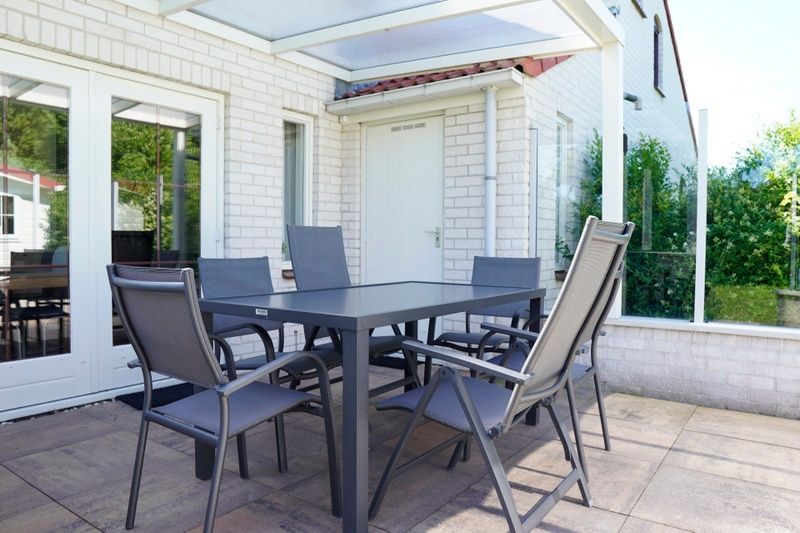 Ontspan op het terras van Vakantiehuis D 415 in De Cocksdorp, Texel, met comfortabele stoelen en een serene tuinomgeving.