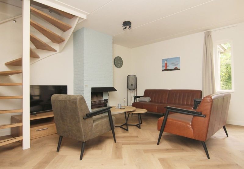 Gemuetliches Wohnzimmer des Ferienhauses D640 in De Cocksdorp, Texel, mit bequemer Sitzecke und modernem Kamin.