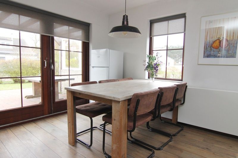 Gemuetliche Essecke im Ferienhaus D 401 in De Cocksdorp, Texel, mit Holztisch und Blick auf den Garten der Watteninseln.