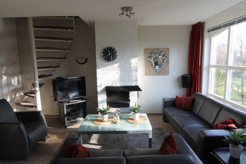 Gezellige woonkamer van Vakantiehuis D 720 in De Cocksdorp, Texel, met comfortabele banken en een sfeervolle open haard.