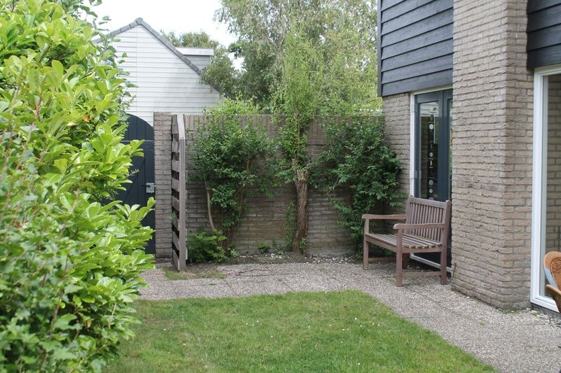 Rustig terras bij Vakantiehuis A 267 in De Cocksdorp, Texel, omringd door groen en perfect voor ontspanning op de Waddeneilanden.