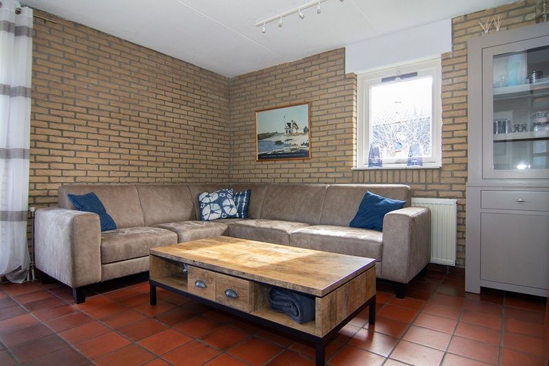 Gezellige woonkamer van Vakantiehuis A 267 in De Cocksdorp, Texel, met comfortabele zitbank en warme sfeer.