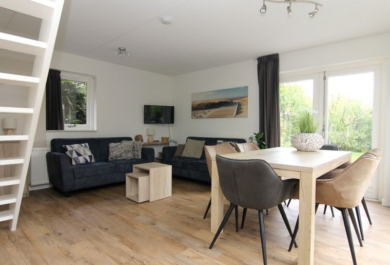 Gezellige woonkamer in Vakantiehuis A 287 in De Cocksdorp, Texel. Comfortabele zithoek en eetruimte met uitzicht op de groene omgeving.