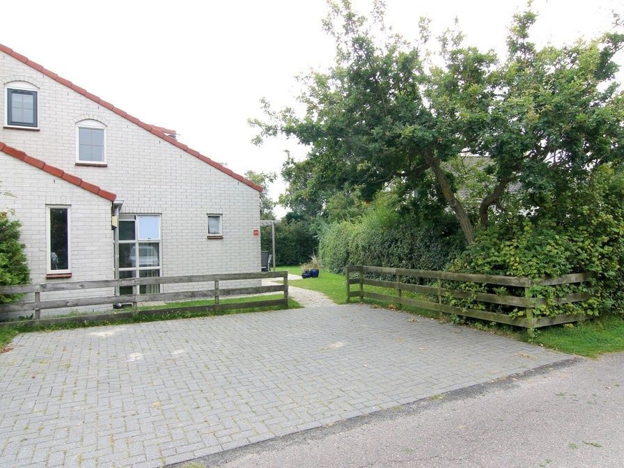 Vakantiehuis D 533 in De Cocksdorp, Texel, biedt een rustige omgeving met groene natuur en een uitnodigend terras voor ontspanning.