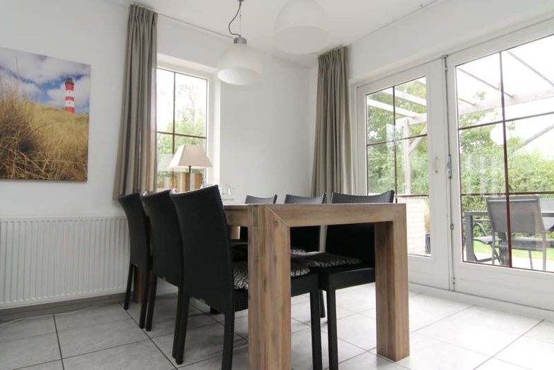 Gezellige eetkamer in Vakantiehuis D 533, De Cocksdorp, Texel, met uitzicht op de tuin via grote ramen, ideaal voor een ontspannen verblijf.