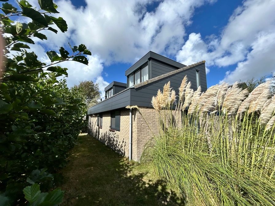 Vakantiehuis A 227 in De Cocksdorp op Texel, Waddeneilanden, omgeven door weelderige natuur en een helderblauwe lucht.